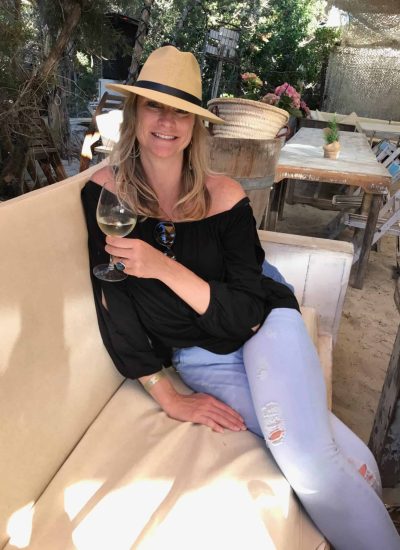 Kim, The Abundant Traveler, sitting on a bench and drinking wine at a restaurant in Spain - My Spain Travel Guide